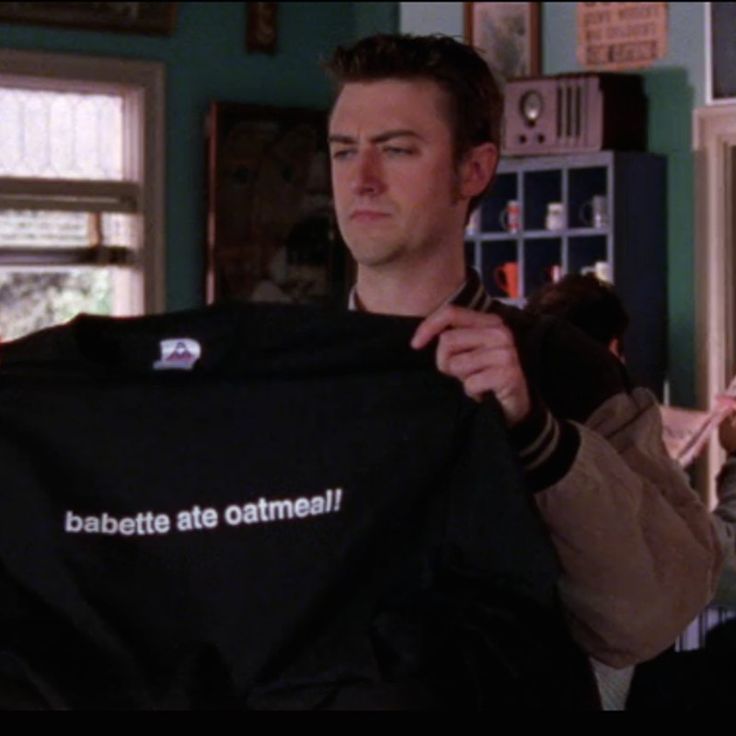 Kirk holding up a black t-shirt that says 'Babette ate oatmeal!' in white text.