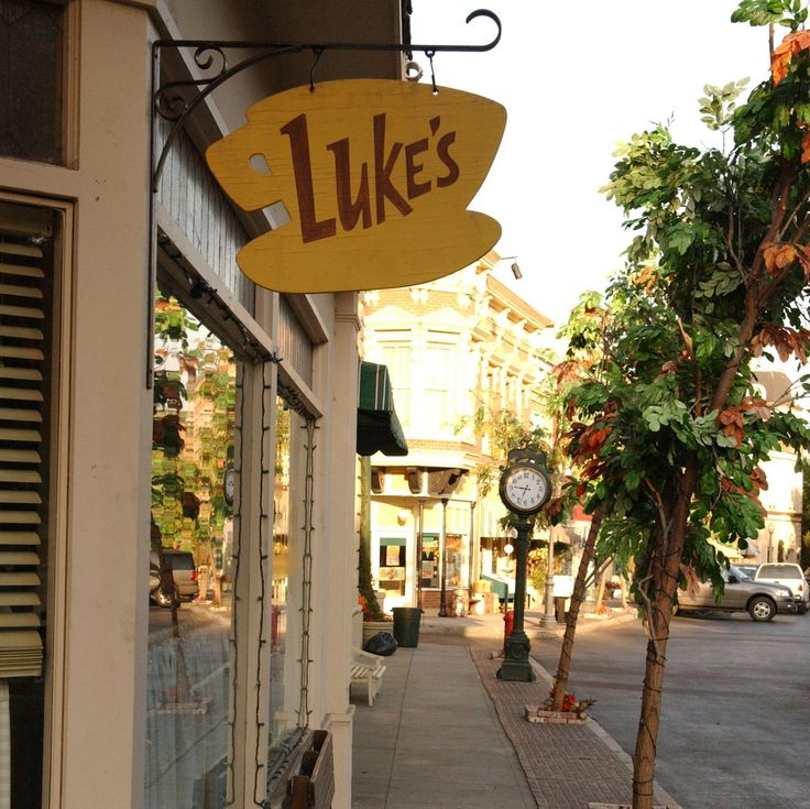 Yellow coffee cup-shaped sign reading 'Luke’s' hanging outside a cozy diner.